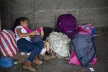 Anita ayuda a dar de comer a un bebé que acaba de conocer mientras espera junto a su madre que salga la Caravana Migrante en dirección a la frontera de Agua Caliente, San Pedro Sula, 14 de enero de 2020. Foto: Fernando Silva.