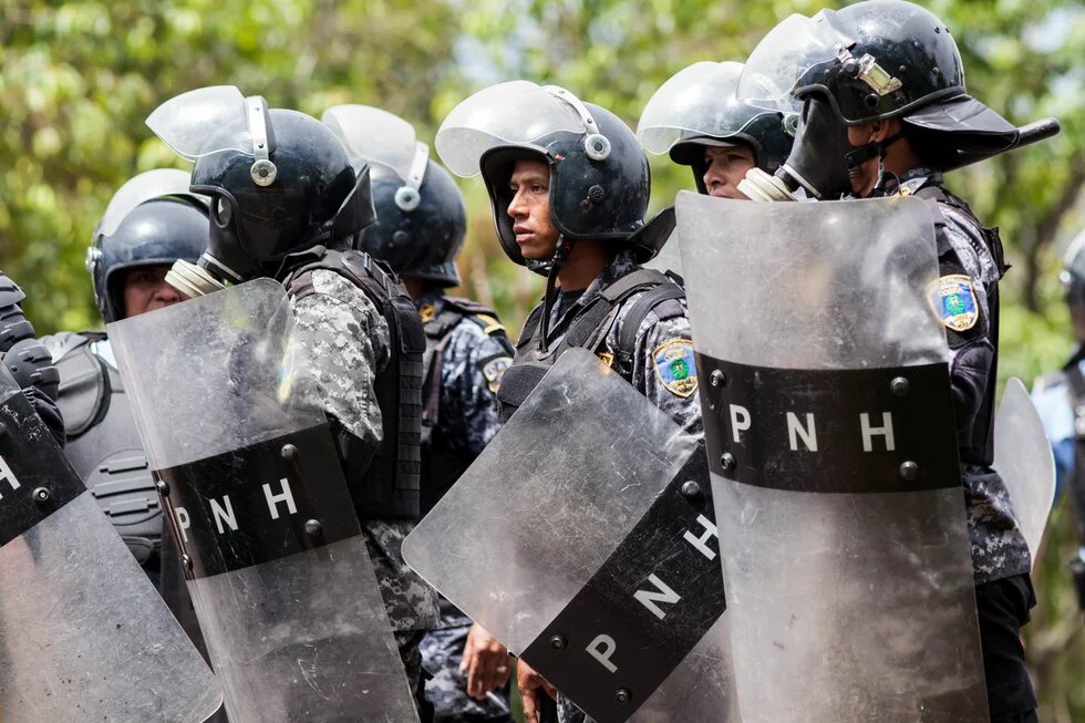 La policía antidisturbios aguarda órdenes para avanzar hacia la Universidad UNAH y comenzar a disparar cartuchos de gas lacrimógeno contra las multitudes de estudiantes que protestan.