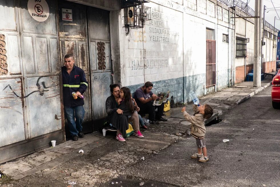 Una familia de hondureños, procedentes de San Pedro Sula, descansa un momento afuera de un taller mecánico en los alrededores de La Casa de Migrante, en Ciudad de Guatemala, el 18 de octubre de 2018.